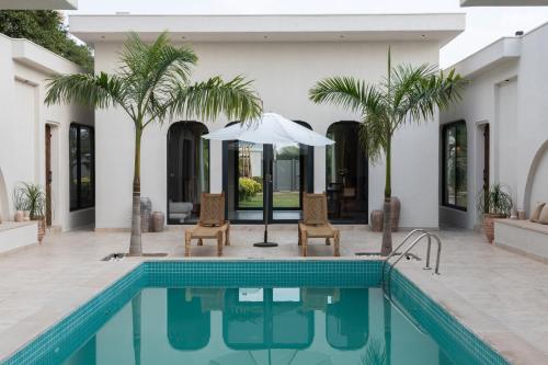 a pool with two chairs and an umbrella next to a house at LA VIDA RETREAT in Jaipur