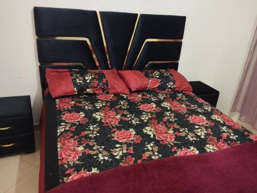 a bed with a black and red quilt and red pillows at caprice appartement in Ifrane