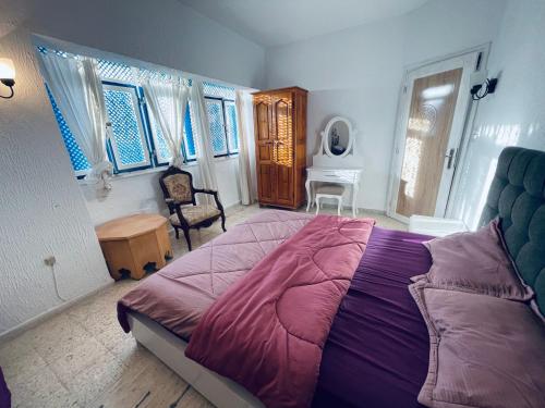 Villa le bon coin de la marsa في المرسى: غرفة نوم بسرير ارجواني كبير وكرسي
