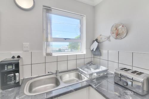 eine Küche mit einem Waschbecken und einem Fenster in der Unterkunft Redsky self catering Agulhas in Agulhas