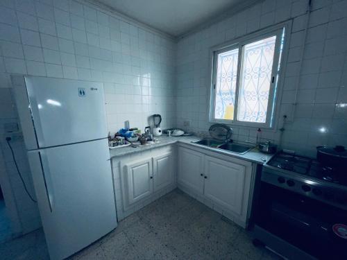 eine Küche mit einem Kühlschrank, einer Spüle und einem Fenster in der Unterkunft Villa le bon coin de la marsa in La Marsa