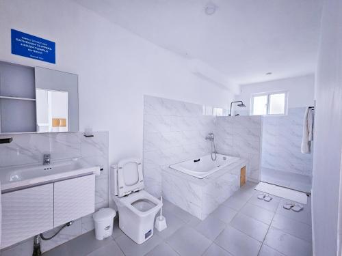 a white bathroom with a toilet and a sink at TAKAWIRI VICTORIA SANDS in Takawiri Island