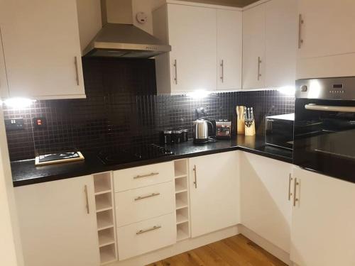 a kitchen with white cabinets and black counter tops at Superb 2Bed/2Bath Flat Waterloo London in London