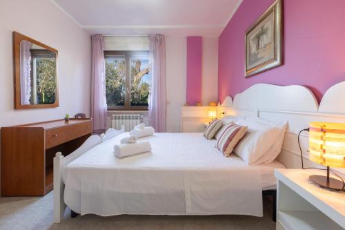 a bedroom with a white bed with pink walls at Villa Vacanze Paradiso - Oasi di Tranquillità con Piscina e Giardino a 10 min dal mare in Neviano