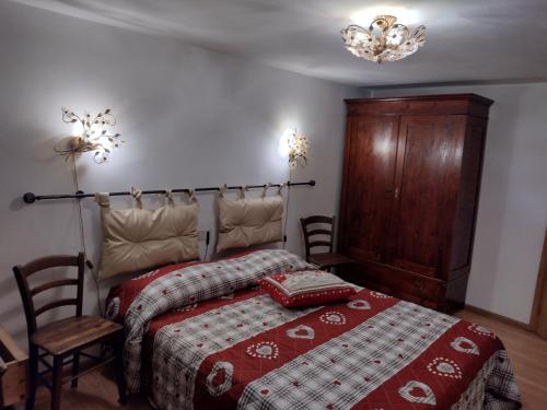 a bedroom with a bed with a red blanket and a wooden cabinet at Casa Sirena in Canale dʼAgordo