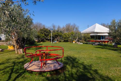 a red bench in a park with a gazebo at Villa Vacanze Paradiso - Oasi di Tranquillità con Piscina e Giardino a 10 min dal mare in Neviano