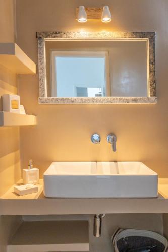 a bathroom with a white sink and a mirror at BLUE WATERS MYKONOS in Ornos