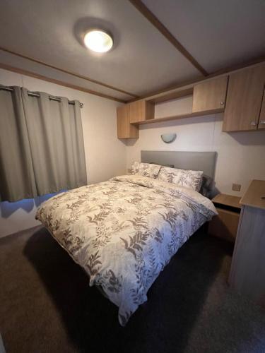 a bedroom with a bed with a blue and white comforter at Coastal Caravan Holidays - Goldfinch 22 in Withernsea