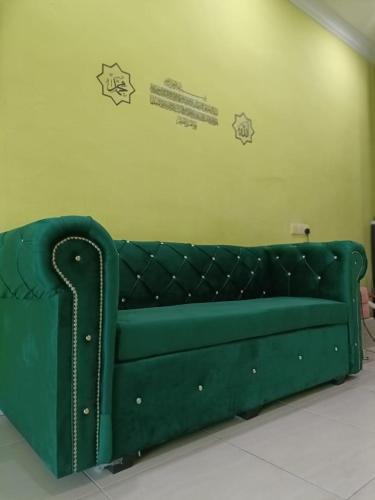 a green couch in a room with stickers on the wall at IRDINA HOMESTAY forMuslims - Changlun in Changlun