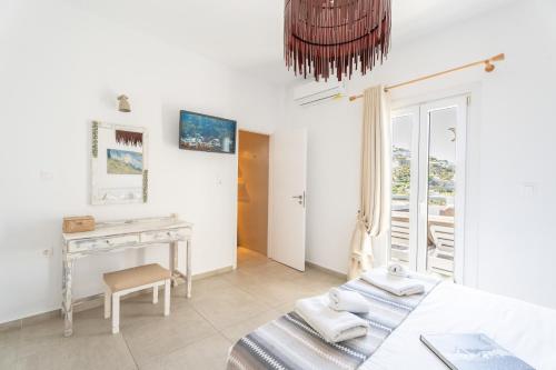 a white room with a desk and a bed at BLUE WATERS MYKONOS in Ornos