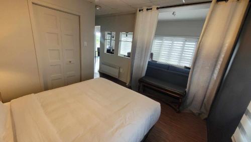 a bedroom with a bed and a window and a chair at Hôtel Aquamer in Carleton sur Mer