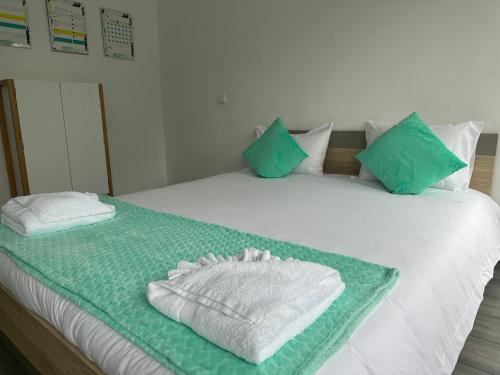 a bed with green and white sheets and blue pillows at MADEIRA SHOPPING- 10min to Funchal in Funchal