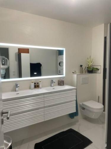 La salle de bains blanche est pourvue d'un lavabo et de toilettes. dans l'établissement T4 Chaleureux et moderne, à Saint-Leu-la-Forêt