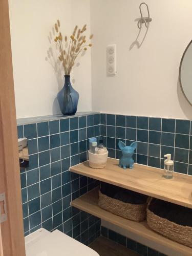 une salle de bains carrelée de bleu avec une étagère et une figurine de chat bleu dans l'établissement La Calanca - Appartement d'hôtes Centre ville de Sète parking gratuit, à Sète