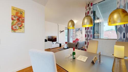 a dining room with a table and gold pendant lights at DünenResort in Binz, strandnahe und moderne FeWos mit Balkon, teilweise mit Meerblick, in Binz