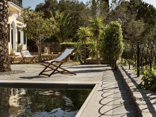 a chair sitting next to a pond in a yard at Almeira 4acre Estate, for Unparalleled Seclusion, By ThinkVilla in Zakynthos