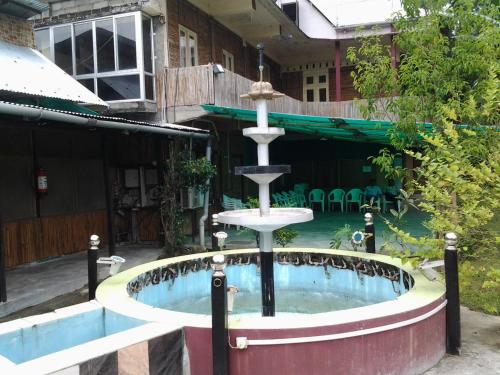 einen Brunnen vor einem Gebäude mit Pool in der Unterkunft Ashrayaa Prakreeti. in Jorhat