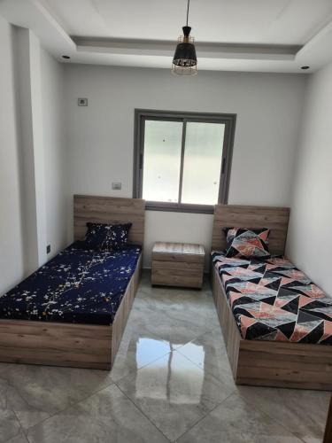 a bedroom with two beds and a window at résidence el yassamine 17 in Bizerte