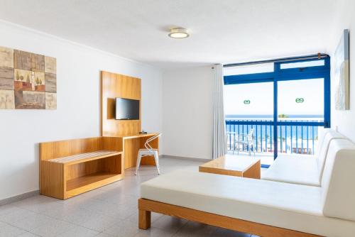 a living room with a white couch and a large window at Ereza Apartamentos Los Hibiscos in Puerto del Carmen