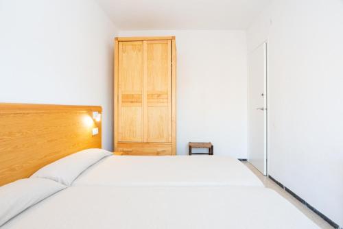 a bedroom with a white bed and a wooden door at Apartamentos Blanes-Condal Costa Brava in Blanes