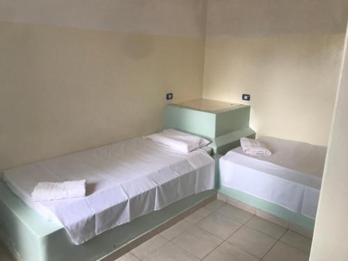 um pequeno quarto com duas camas com lençóis brancos em Maio Relax em Vila do Maio