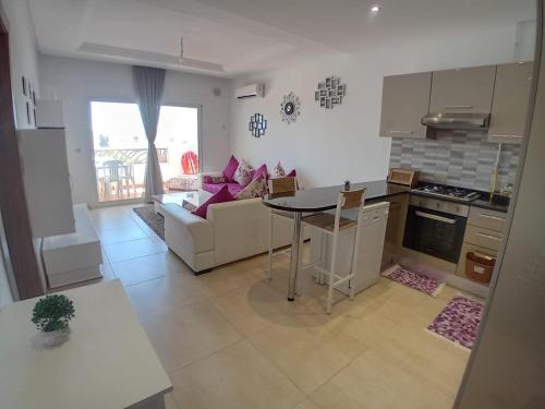 eine Küche und ein Wohnzimmer mit einem Tisch und einem Sofa in der Unterkunft Palm Lake Ressort Monastir S2 in Monastir