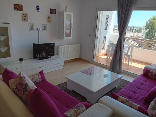 ein Wohnzimmer mit einem lila Sofa und einem Tisch in der Unterkunft Palm Lake Ressort Monastir S2 in Monastir