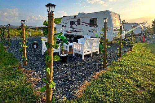 een camper geparkeerd in een tuin met een bank en een tafel bij Son de Mar Camper - Shared Pool near to the Beach in Arecibo