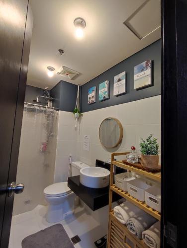 ein Badezimmer mit einem WC, einem Waschbecken und einem Spiegel in der Unterkunft RC Staycation in Manila