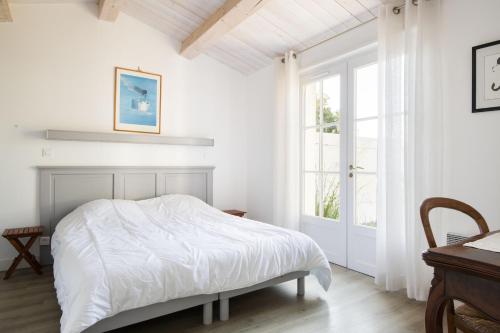 ein weißes Schlafzimmer mit einem Bett und einem Fenster in der Unterkunft LATITUDE46 maison de charme à Sainte Marie de Ré in La Noue