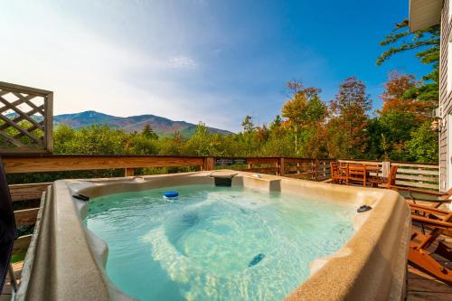 a hot tub on a deck with mountains in the background at Stunning Views, Luxury, Near Whiteface,Lake Placid in Wilmington