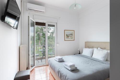 a white bedroom with a bed and a balcony at Olympic Hadrian view apartment! in Athens