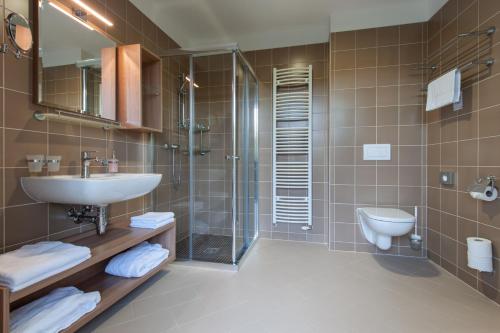 a bathroom with a sink and a shower and a toilet at Lázeňský dům Praha in Hranice
