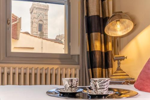 una mesa con dos vasos y una lámpara y una ventana en L'Alcova di Giotto, en Florencia