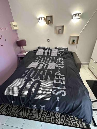une chambre avec un lit avec une couette noire et blanche dans l'établissement Studio purple proche Paris, à Chennevières-sur-Marne