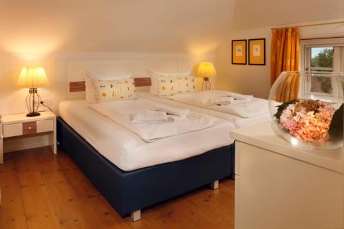 2 Betten in einem Zimmer mit 2 Tischen und 2 Lampen in der Unterkunft Wattwanderer in Oldsum