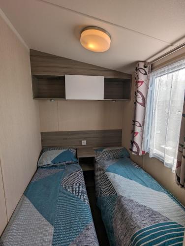 Habitación pequeña con 2 camas y TV. en Relaxing Holiday Home Chickerell View Littlesea Haven, en Weymouth
