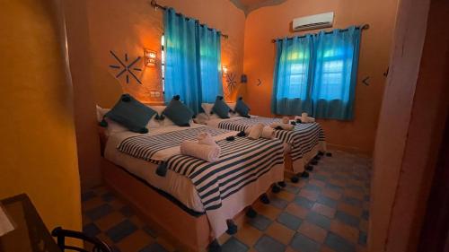 a bedroom with a large bed with blue curtains at Riad Dar Poublanc in Merzouga
