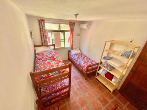 a small room with two beds and a shelf at Ap da Tia Fê no paraíso da Praia de Morro Branco in Fortaleza