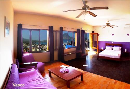 uma sala de estar com um sofá, uma cama e janelas em Solar Windelo em Mindelo