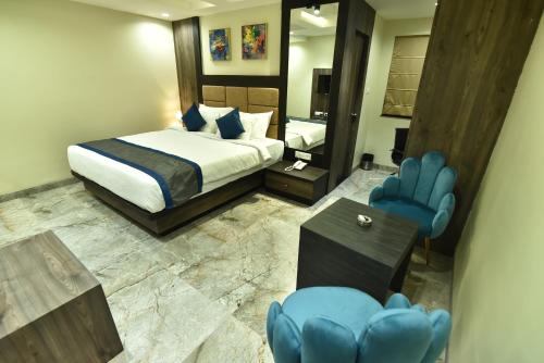 Habitación de hotel con cama y sillas azules en HOTEL RAINDROP, en Durgāpur