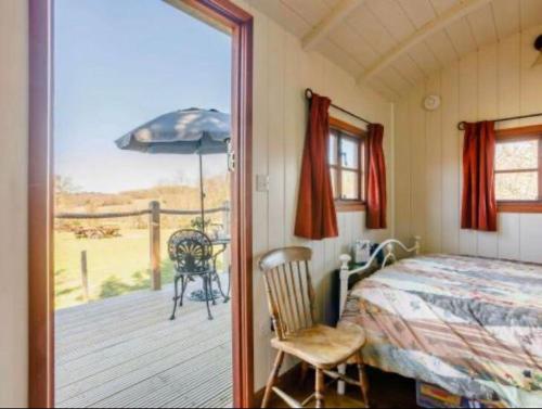 een slaapkamer met een bed en een balkon met een parasol bij Pooks Rest in Hurst Green