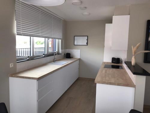 a kitchen with white cabinets and a large window at Residentie Sluispark in Ghent