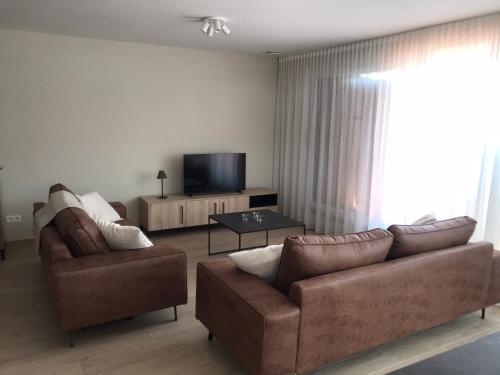 uma sala de estar com 2 sofás e uma televisão de ecrã plano em Residentie Sluispark em Gent