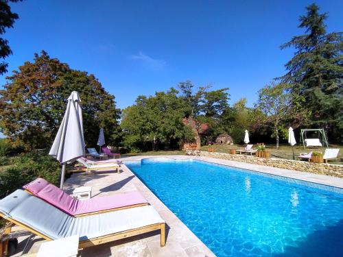 ein Swimmingpool mit zwei Stühlen und einem Sonnenschirm in der Unterkunft La Borie du Cambord - Gîtes et Chambres d'hôtes in Sarlat-la-Canéda