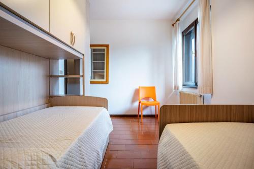 1 dormitorio con 2 camas y silla naranja en Garden alle barche - Marina 7, en Calceranica al Lago