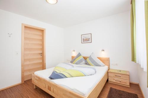 a bedroom with a bed with white sheets and blue pillows at Conny's Apartments in Neustift im Stubaital