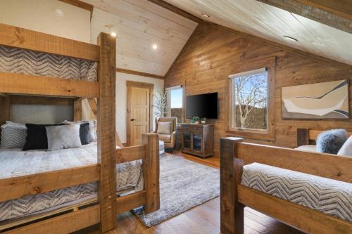 ein Schlafzimmer mit zwei Etagenbetten und einem Fernseher in der Unterkunft Sunset Ridge Mountain Luxury Villa in Mineral Bluff