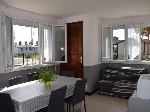 une salle à manger avec une table, des chaises et des fenêtres dans l'établissement Appartement 6 pers, terrasse, parking, centre Marseillan Plage - FR-1-387-158, à Marseillan
