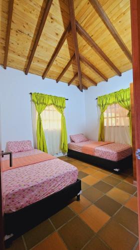 2 Betten in einem Zimmer mit grünen Vorhängen in der Unterkunft mesa de los santos in La Fuente